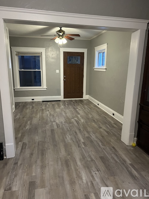 A room with a ceiling fan and wood flooring.