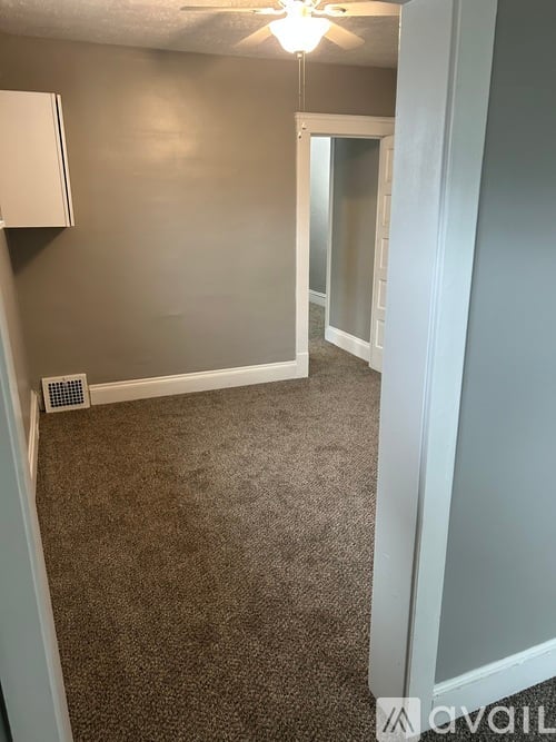 A room with a carpeted floor and a ceiling fan.