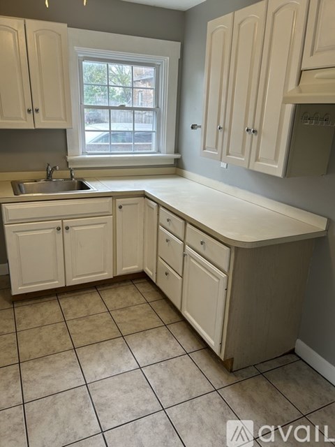 A kitchen with white cabinets and a tiled floor.