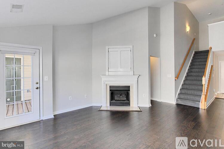 A bright, empty living room with a fireplace and stairs leading to another room.