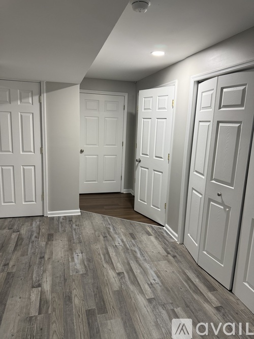 A room with white doors and wooden flooring.