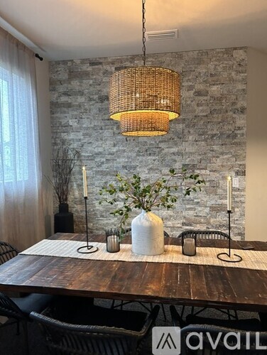 A dining room with a wooden table and a hanging light fixture.