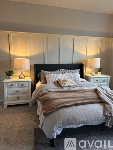 A bedroom with a large bed, two nightstands with lamps, and a carpeted floor.