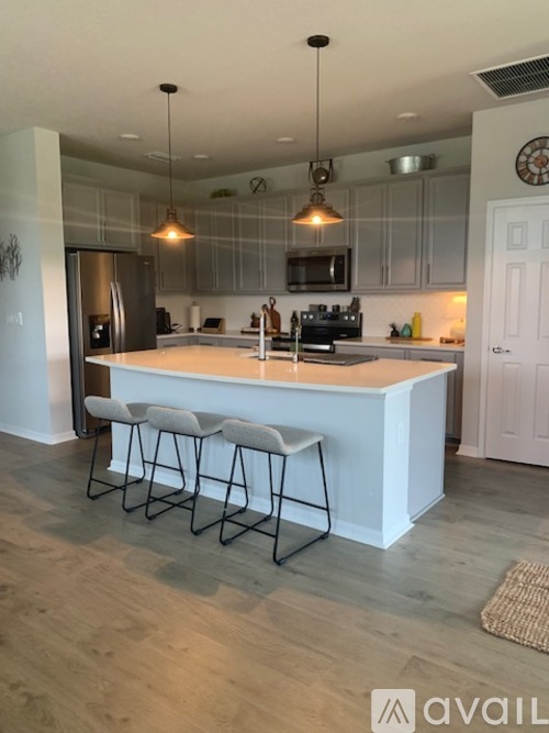 A kitchen with a white island and bar stools.