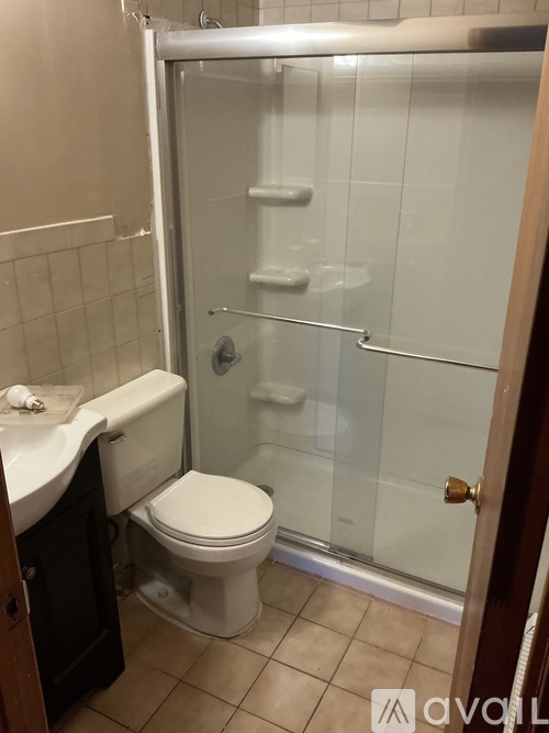 A white toilet in a small bathroom with a glass shower door.