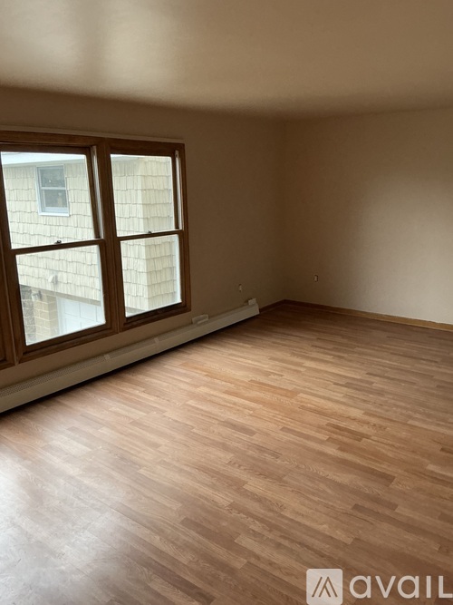 A room with wooden flooring and a window showing a building outside.