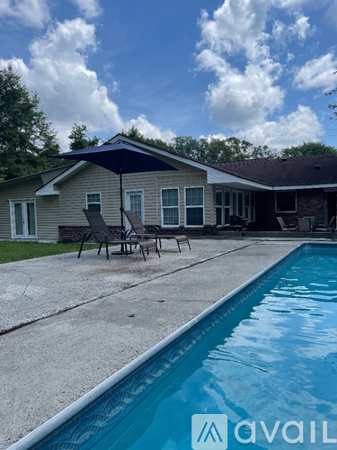 A pool in front of a house with a blue sky and clouds.