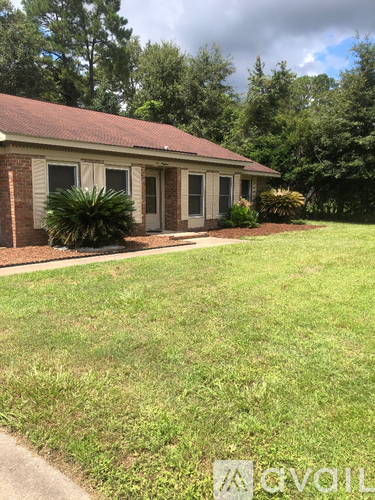 A small house with a brown roof and a white door is surrounded by a grassy lawn.
