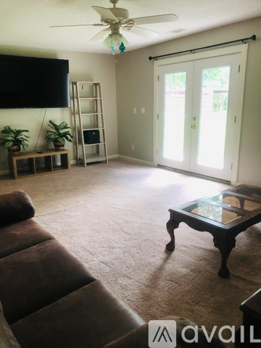 A living room with a brown couch and a glass table.