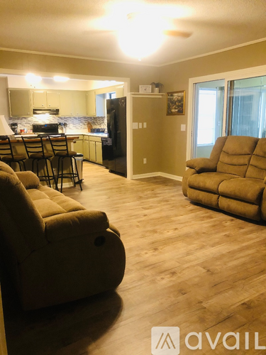 A living room with a couch, chairs, and a kitchen area.