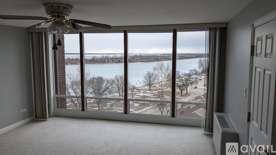 A room with a ceiling fan and large windows overlooking a snowy landscape.