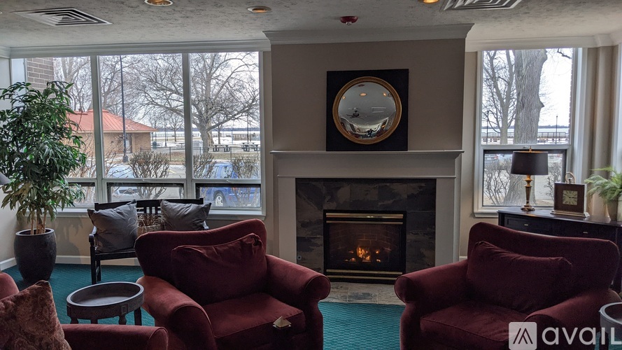 A living room with a fireplace and two red chairs.