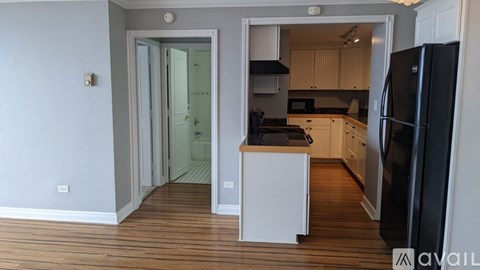 A kitchen with a black fridge and white cabinets.