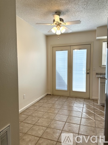 A room with a ceiling fan and a door with a glass panel.