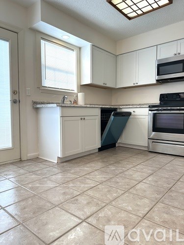 A kitchen with white cabinets and a tiled floor.