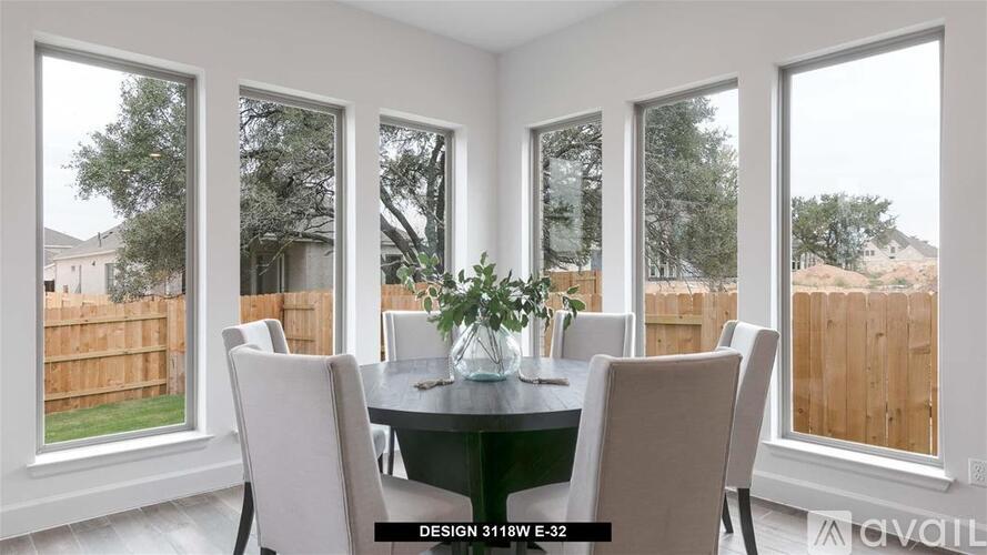 A dining room with a table and chairs and a view of a backyard.