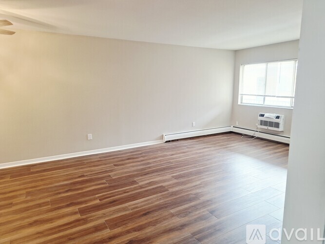 A room with wooden flooring and a window with blinds.
