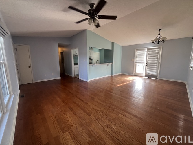 A spacious room with wooden flooring and a ceiling fan.
