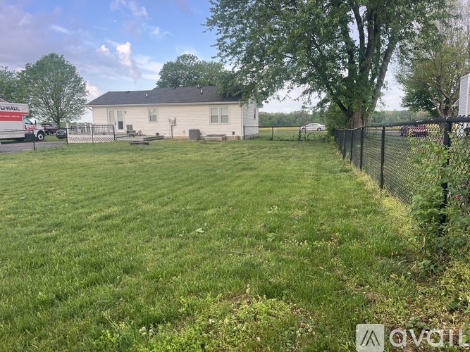 A grassy field with a house and a fence in the background.