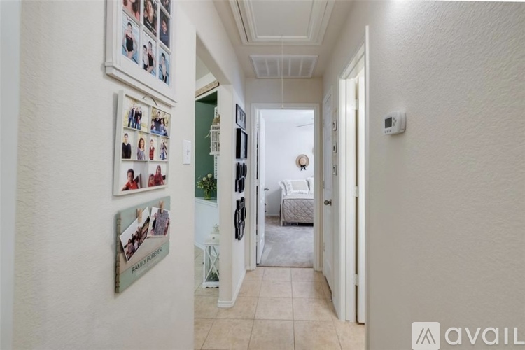 A hallway with pictures on the wall and a bedroom at the end.
