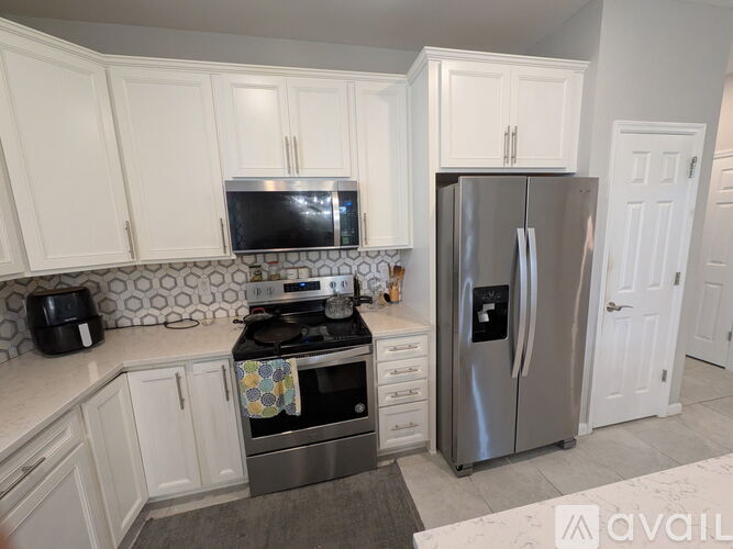A kitchen with white cabinets and a stainless steel refrigerator.