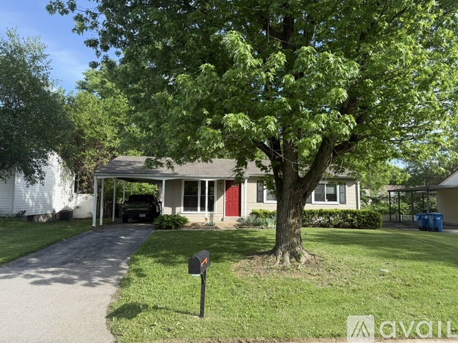 A house with a red door is surrounded by greenery.