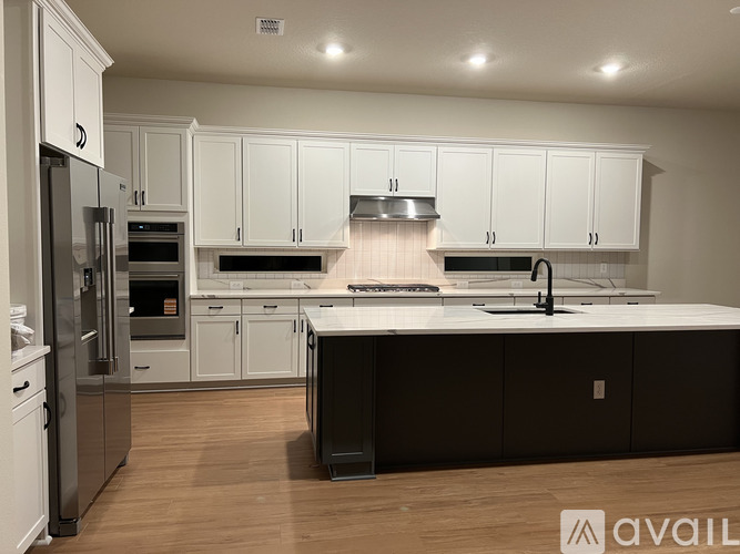 A modern kitchen with white cabinets and a black island.