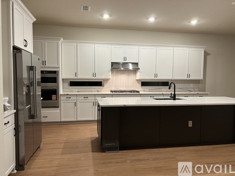 A modern kitchen with white cabinets and a black island.