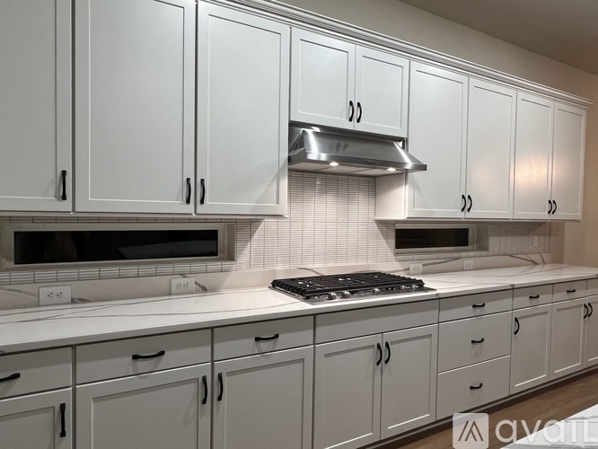 A kitchen with white cabinets and a stainless steel range hood.