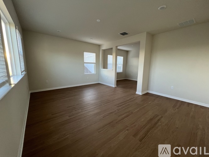A spacious room with wooden flooring and white walls.