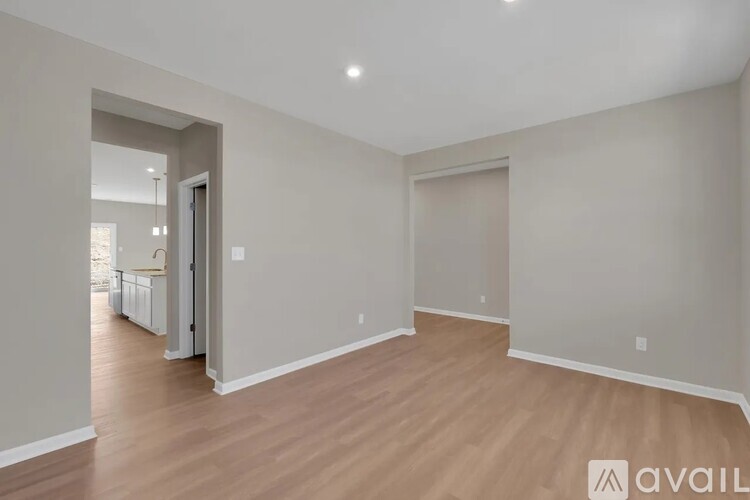 A spacious room with wooden flooring and white walls.