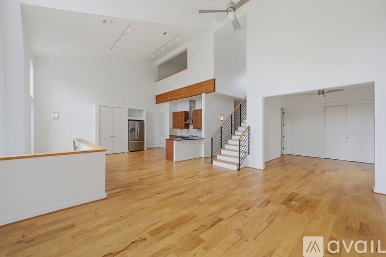 A spacious room with wooden floors and a staircase leading to another level.