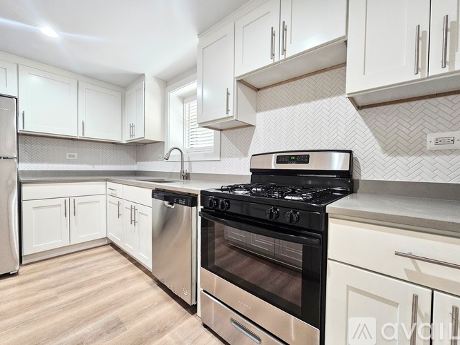 A modern kitchen with a stainless steel oven and white cabinets.