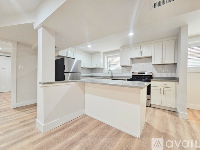 A kitchen with white cabinets and a wooden floor.