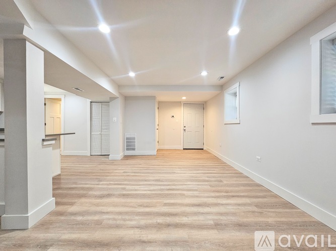 A spacious room with wooden flooring and white walls.