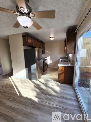 A kitchen with a fan and wooden floors.