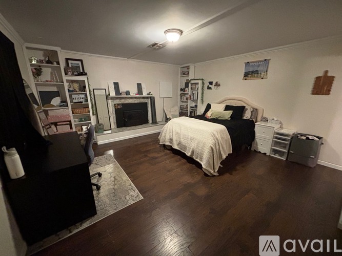 A bedroom with a bed, dresser, and a fireplace.