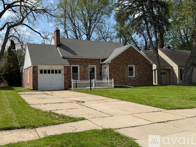 A house with a brick exterior and a white fence is for sale.
