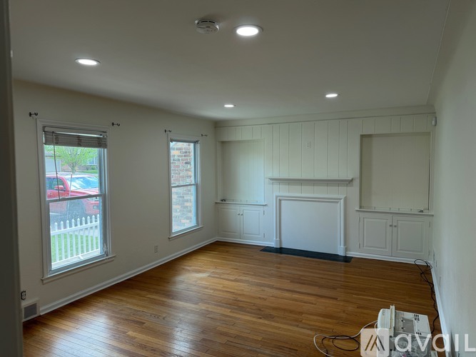 A room with wooden floors and white walls is available for rent.