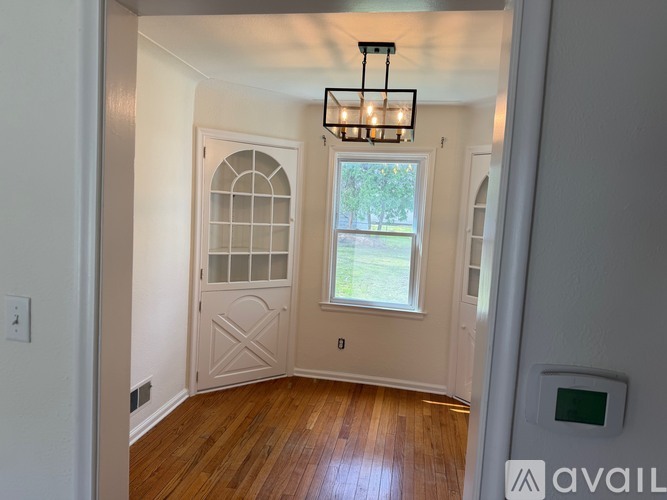 A room with a wooden floor and a window with a view of a lawn outside.