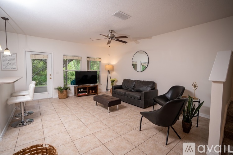 A living room with a black leather couch and a white chair.