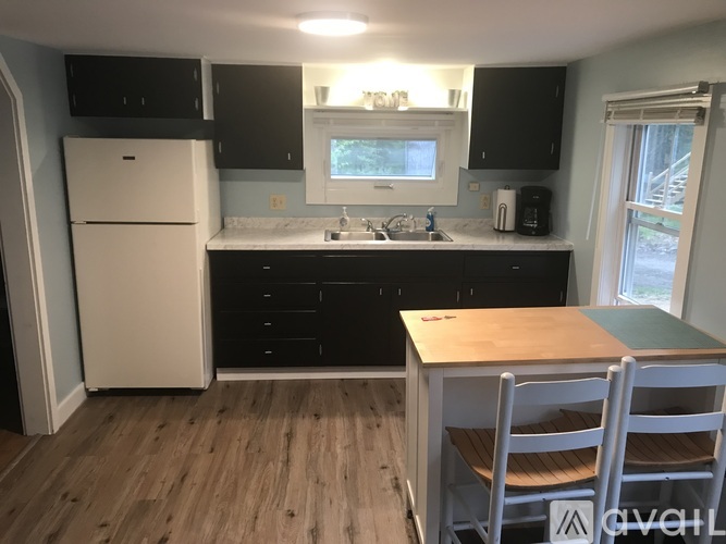 A kitchen with a white fridge, black cabinets, and a wooden table.