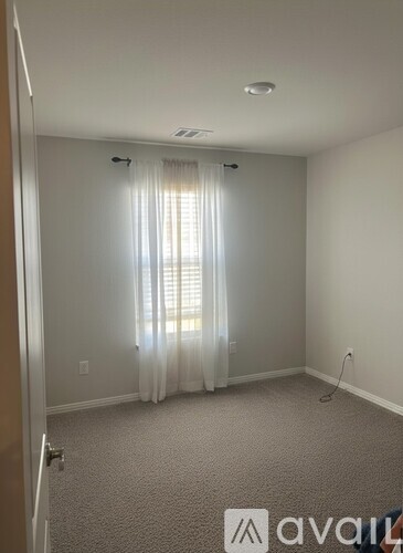 A room with a carpeted floor and a window with curtains.