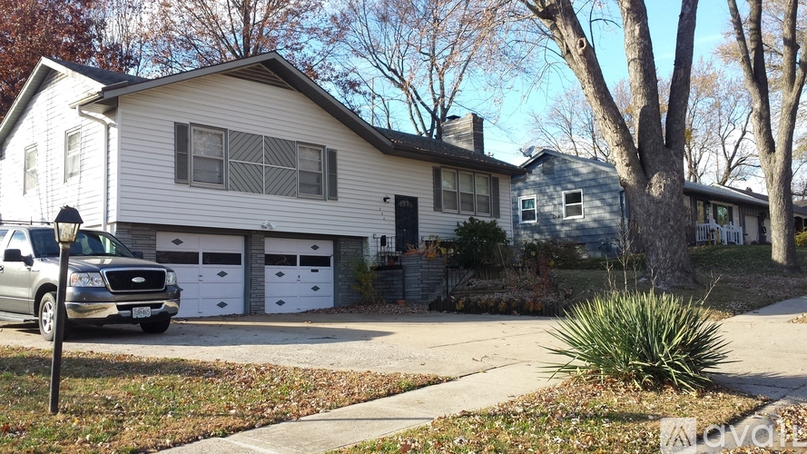 A house with a white garage door is in front of a tree.
