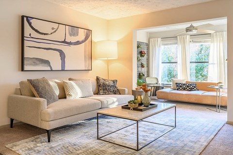 A living room with a beige couch, a coffee table, and a large abstract painting on the wall.