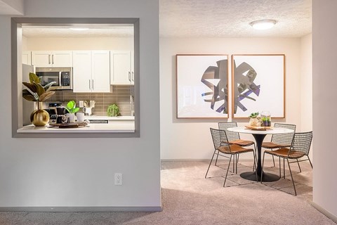 A dining room with a table set for two and a large abstract painting on the wall.
