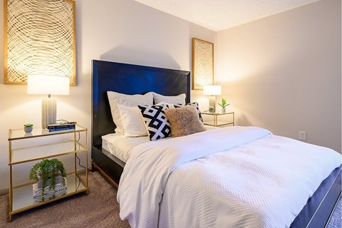 A bedroom with a large bed and a gold-framed mirror on the wall.