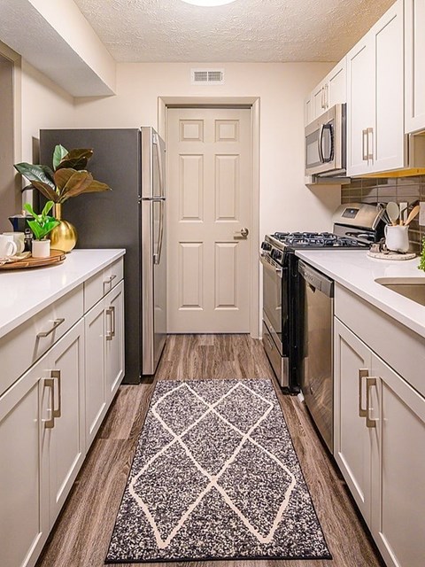 A kitchen with a black fridge and a black stove top.