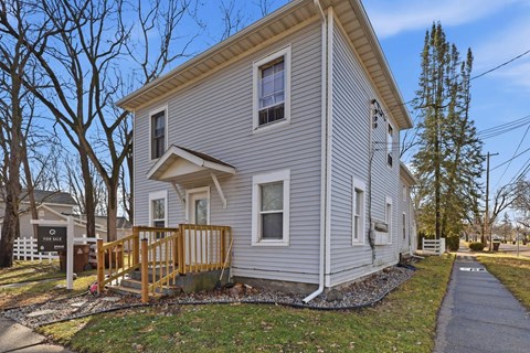 A house with a grey siding and a brown wooden deck.