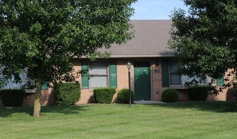 A house with a green door and a tree in front.